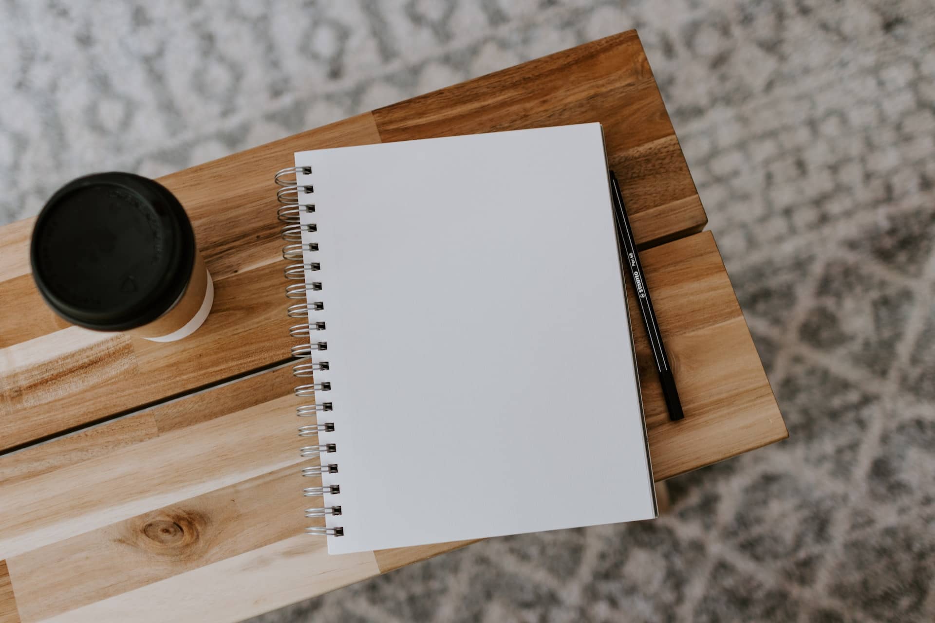 Op deze foto van Kelly Sikkema zie je een notitieboek waarin je ondernemerslessen uit kwartaal 1 kan opschrijven. Daarnaast staat een koffie to go.