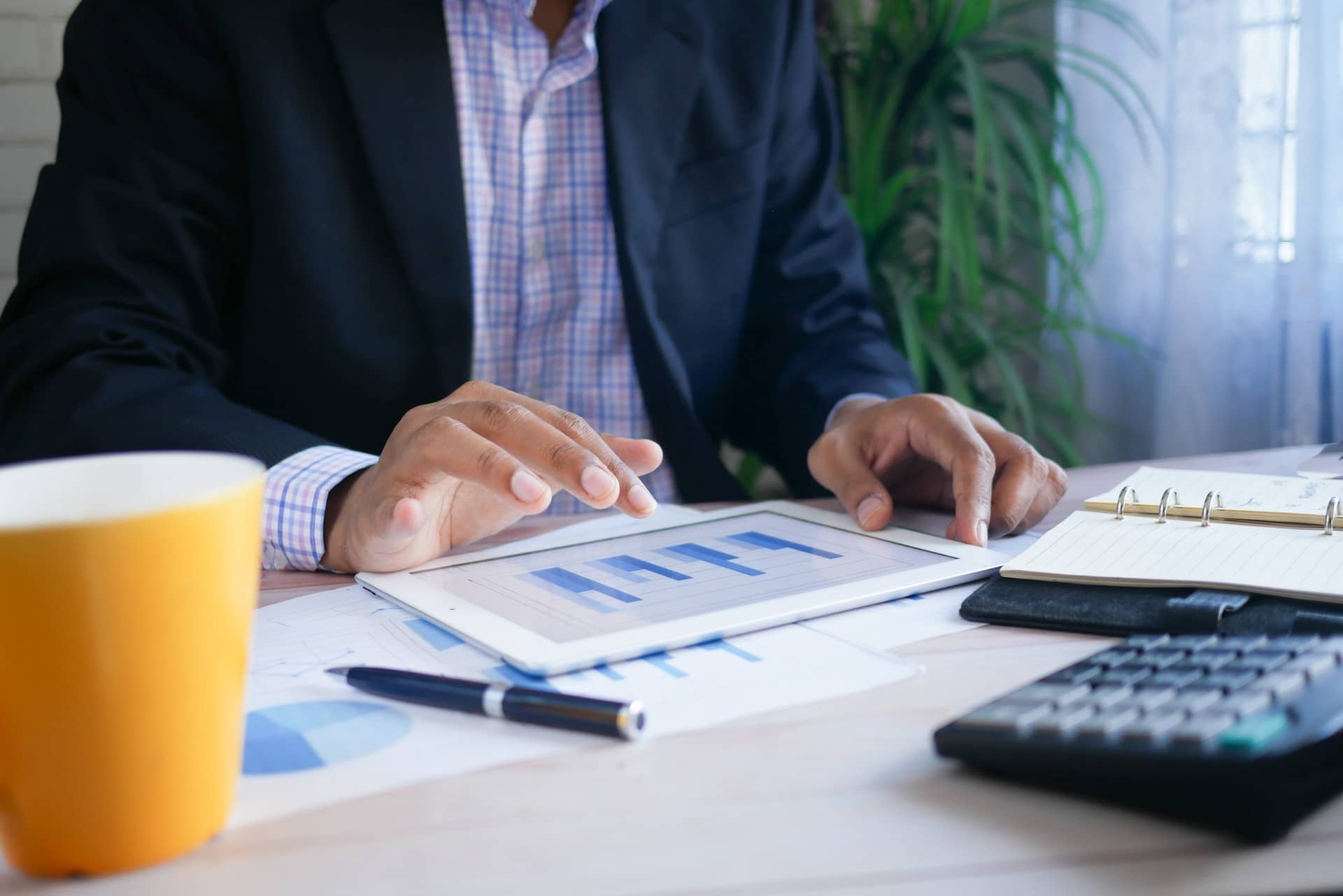 Op de afbeelding is een man in pak te zien die aan zijn bureau zit en bezig is met een financieel plan voor zijn ondernemersplan.